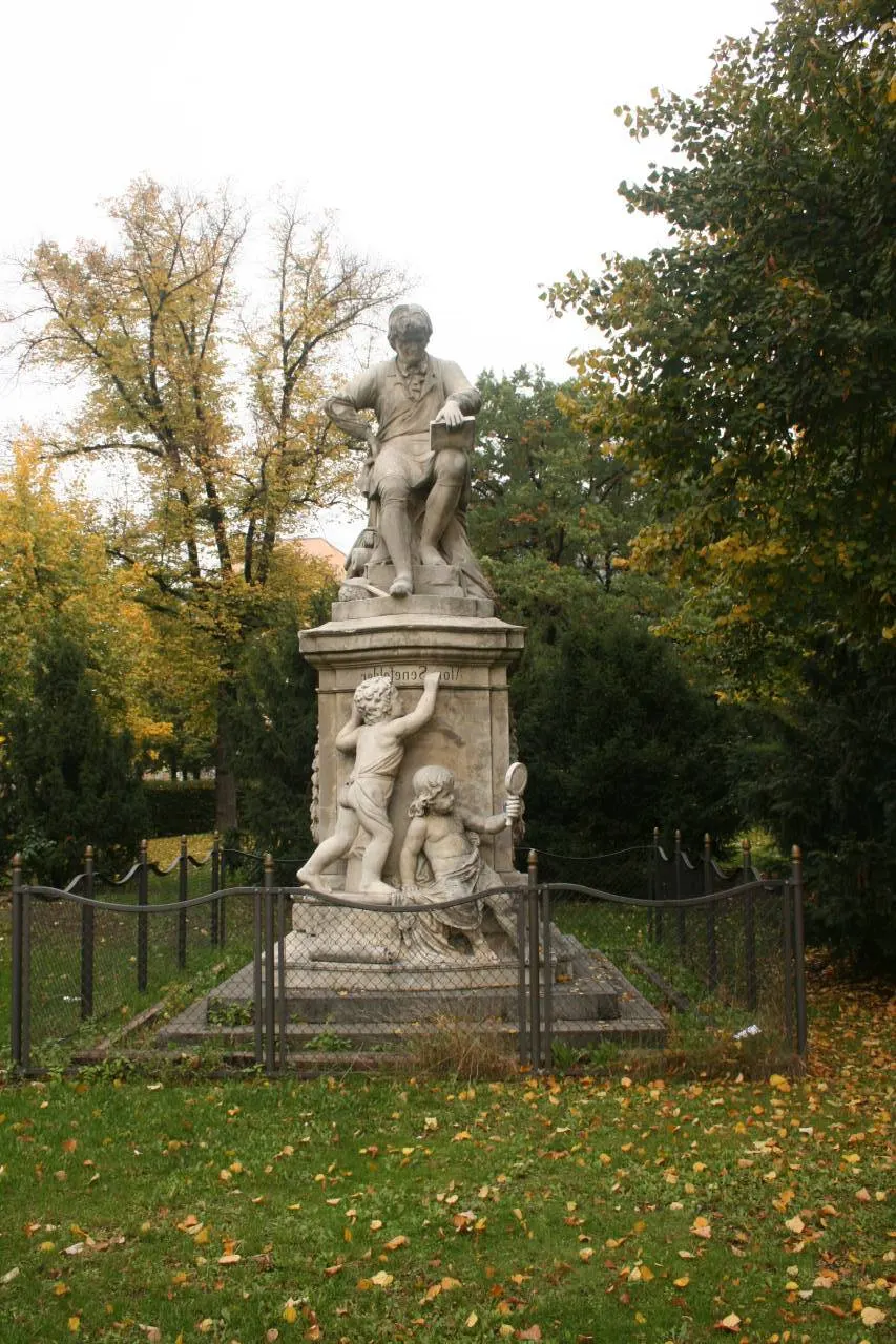 Steinernes Denkmal mit Figurengruppe auf einem Sockel in einem Park