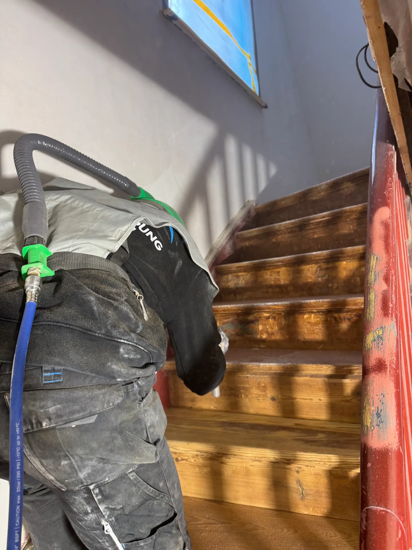 Mitarbeiter strahlt eine Holztreppe: die unteren Stufen zeigen schon helles Holz, die oberen noch die dunkle Beschichtung