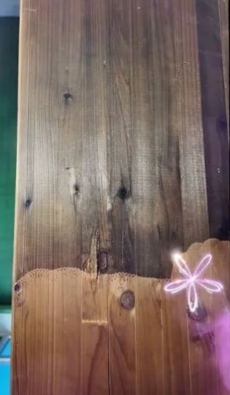 Holzdielen während der Laserreinigung: die untere Hälfte ist bereits abgetragen