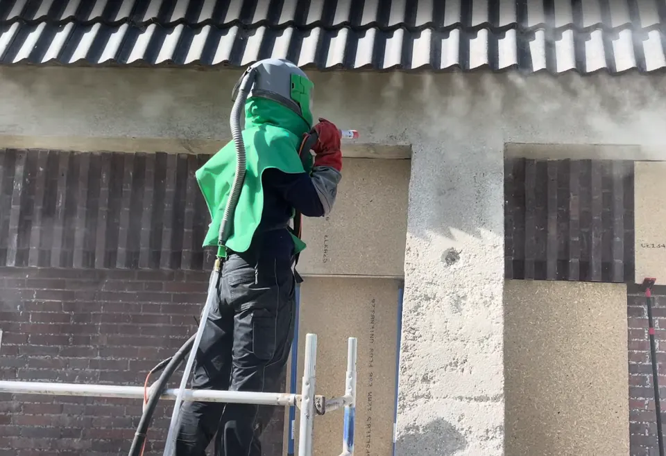 Mitarbeiter auf einem Gerüst beim Strahlen eines Betonpfeilers und Betonsturzes in einer Klinkerfassade
